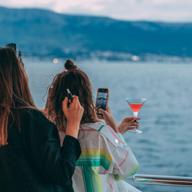 Two girls photographing their cocktails on a sunset cruise