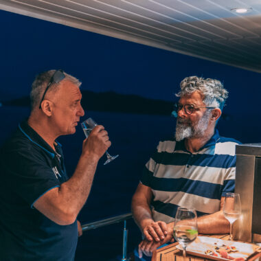 Two friends enjoying the bar onboard during a sunset sail.